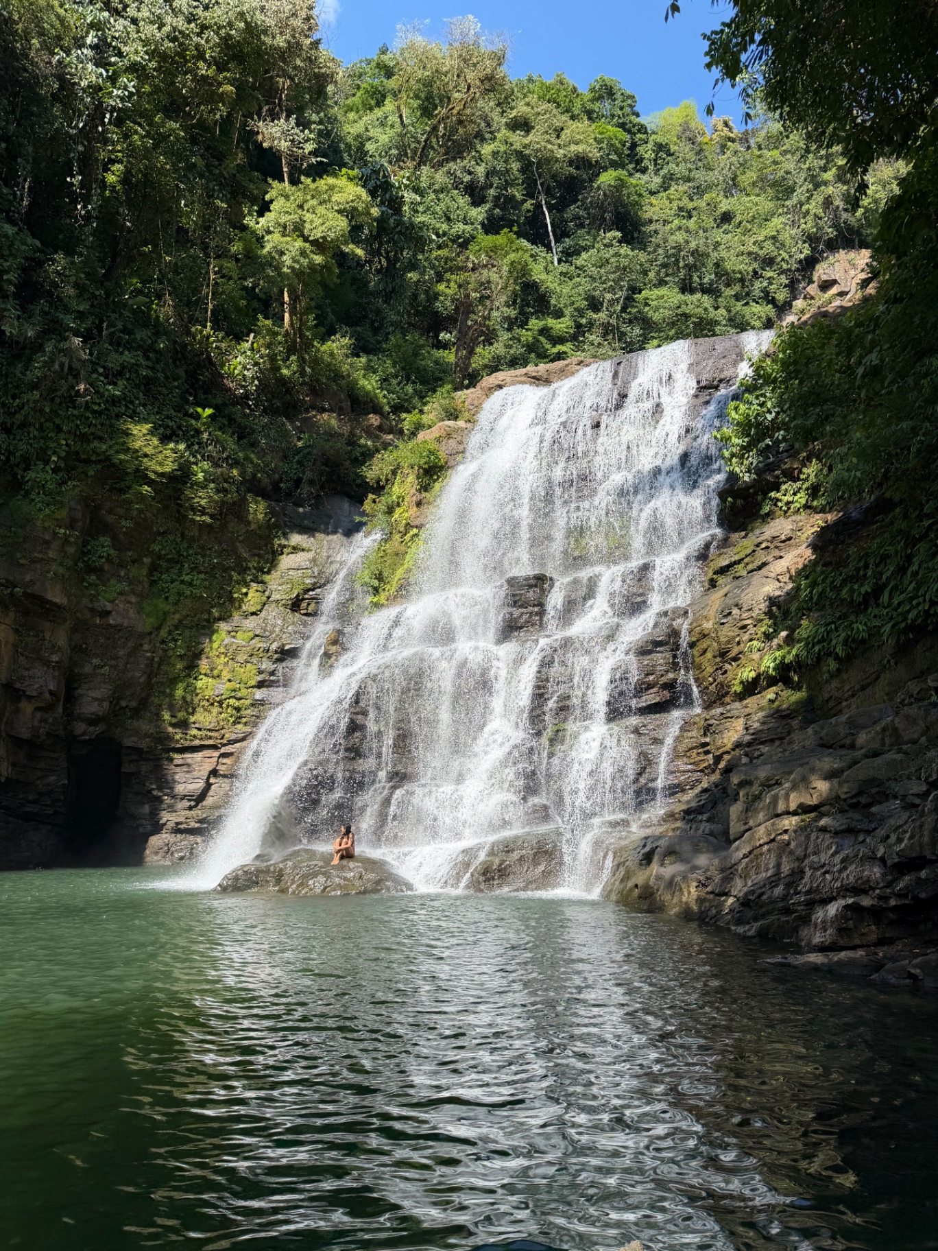 Guest swimming beneath a jungle waterfall in Costa Rica